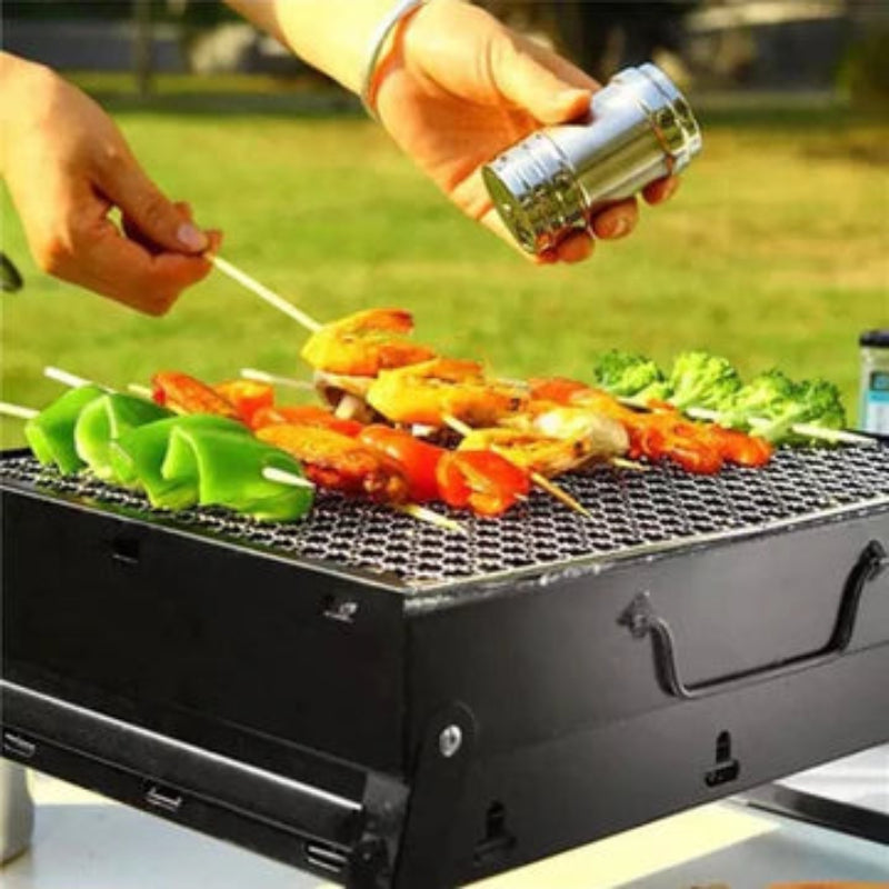Person grilling vegetables on a portable barbecue grill outdoors.