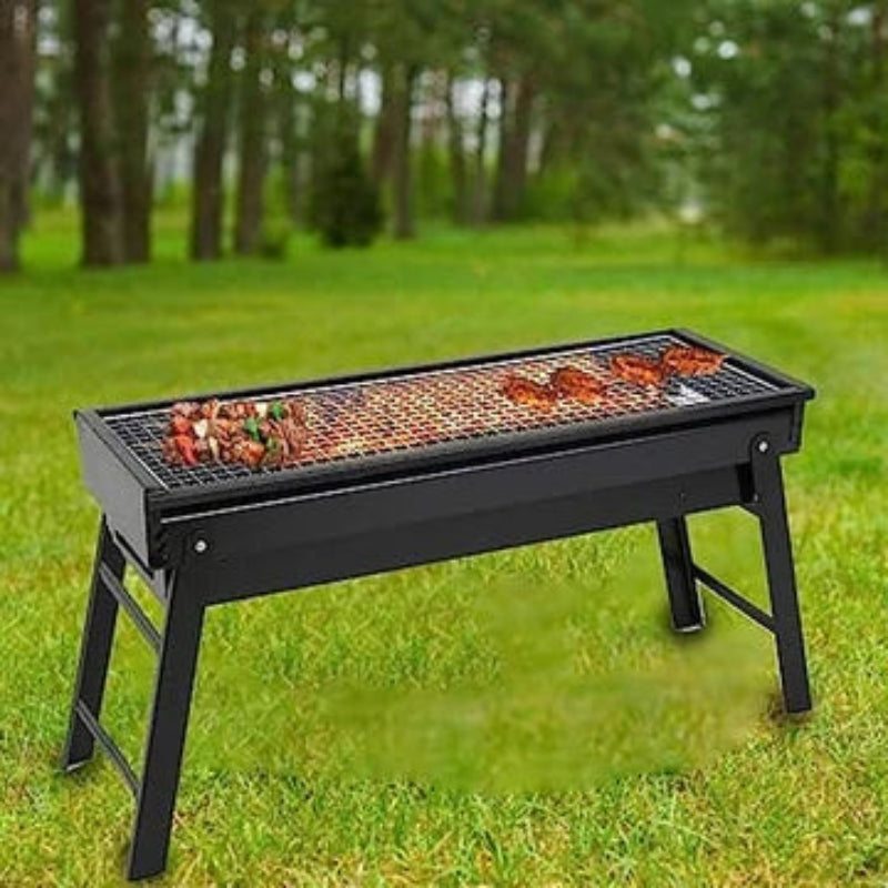 Black portable grill with food on a grassy outdoor area