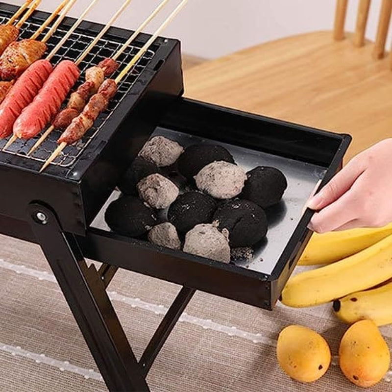 Portable grill with skewered food and coal on a table