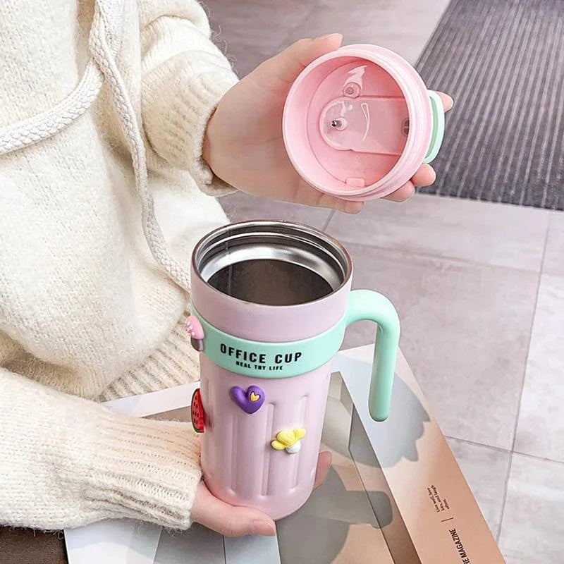 Person holding a pink and green insulated mug with a lid.